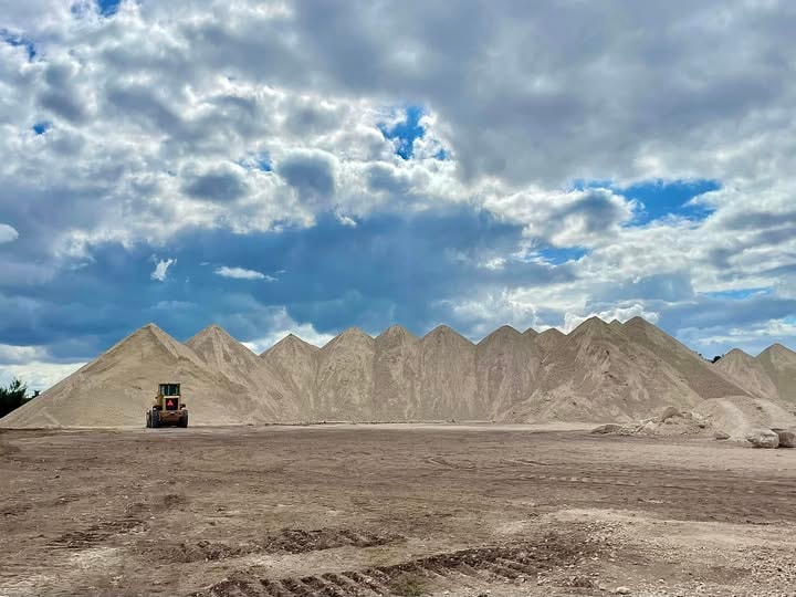 Large crushed rock and gravel aggregate piles with front loader at job site