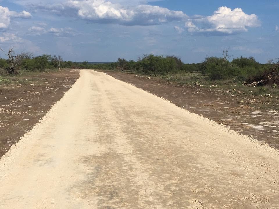 Freshly built caliche road through West Texas brush country under blue sky